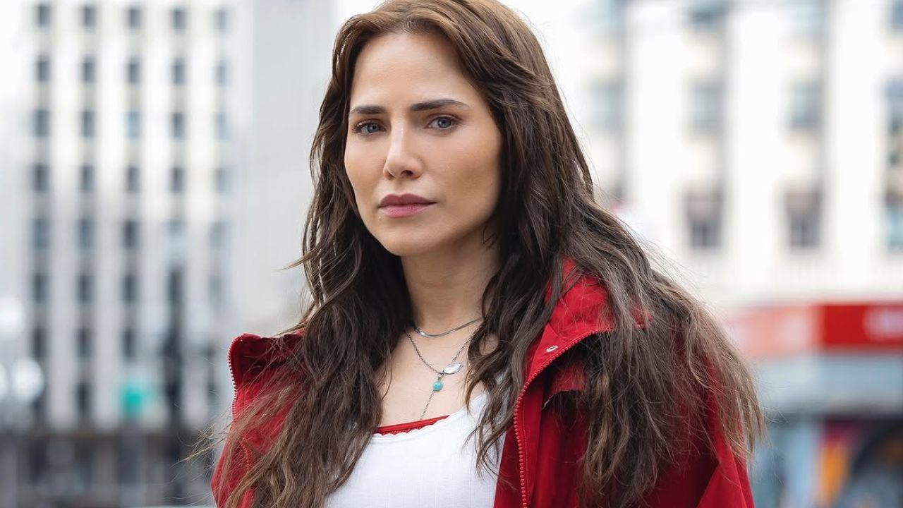 Foto mostra a atriz Leticia Colin. Mulher branca, cabelo castanho claro, usando blusa branca e jaqueta vermelha.